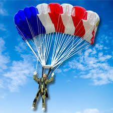 Parachutist descending under a red, white, and blue parachute against a blue sky