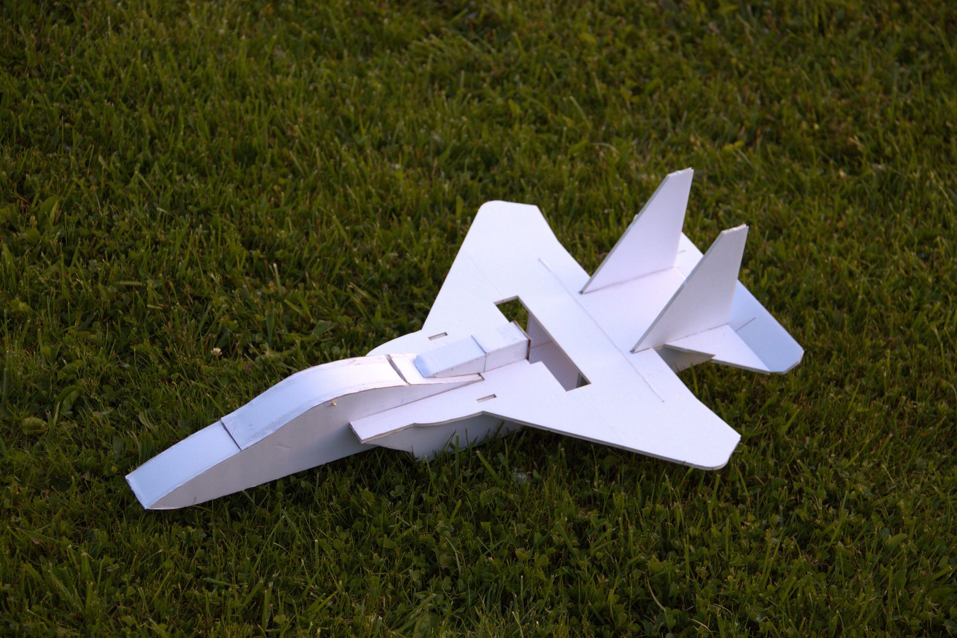 A paper airplane is sitting on top of a lush green field.