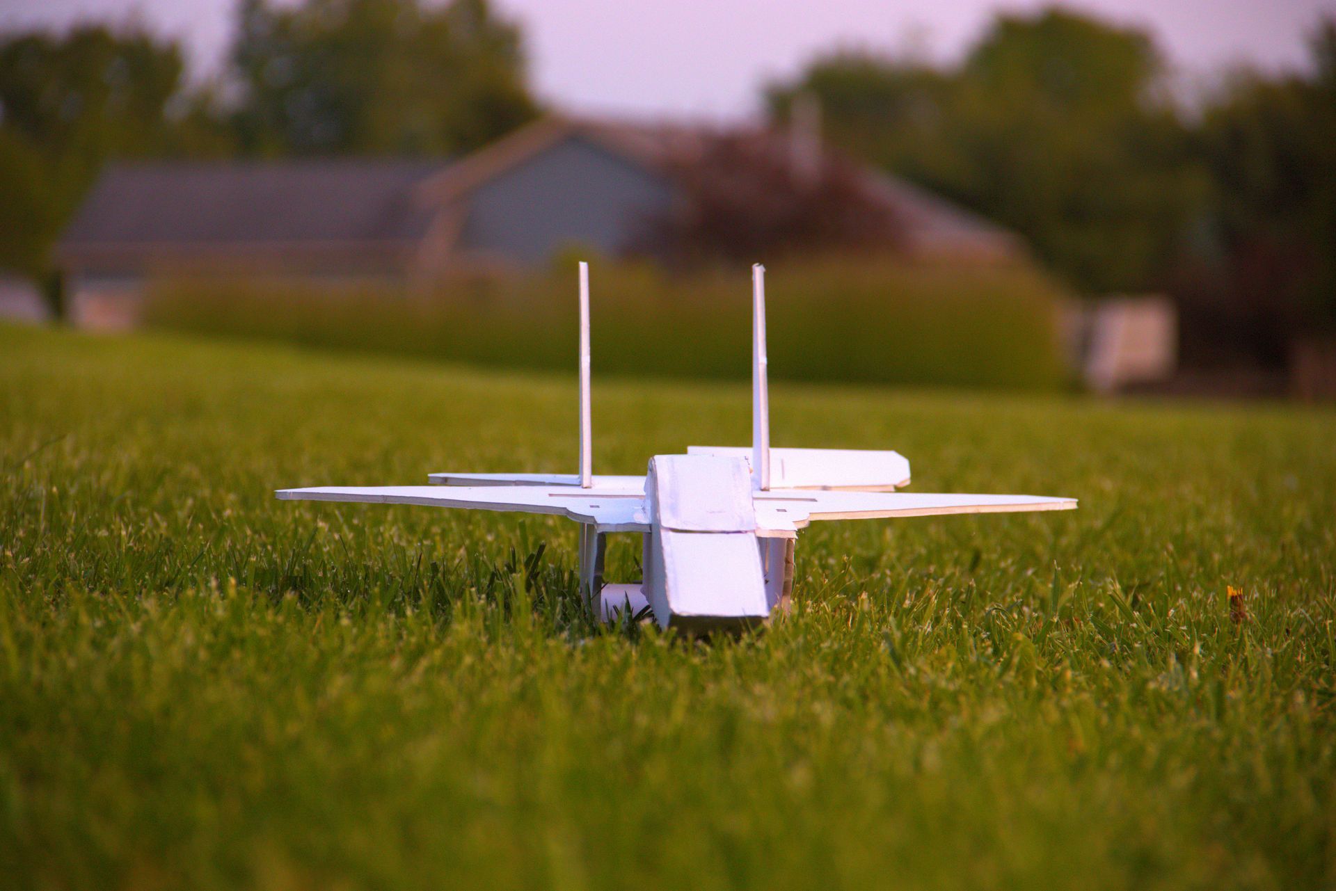 A paper airplane is sitting on top of a lush green field.