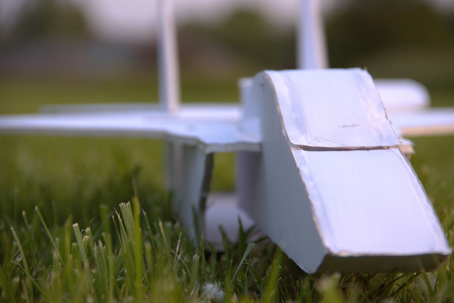 A paper airplane is sitting on top of a lush green field.