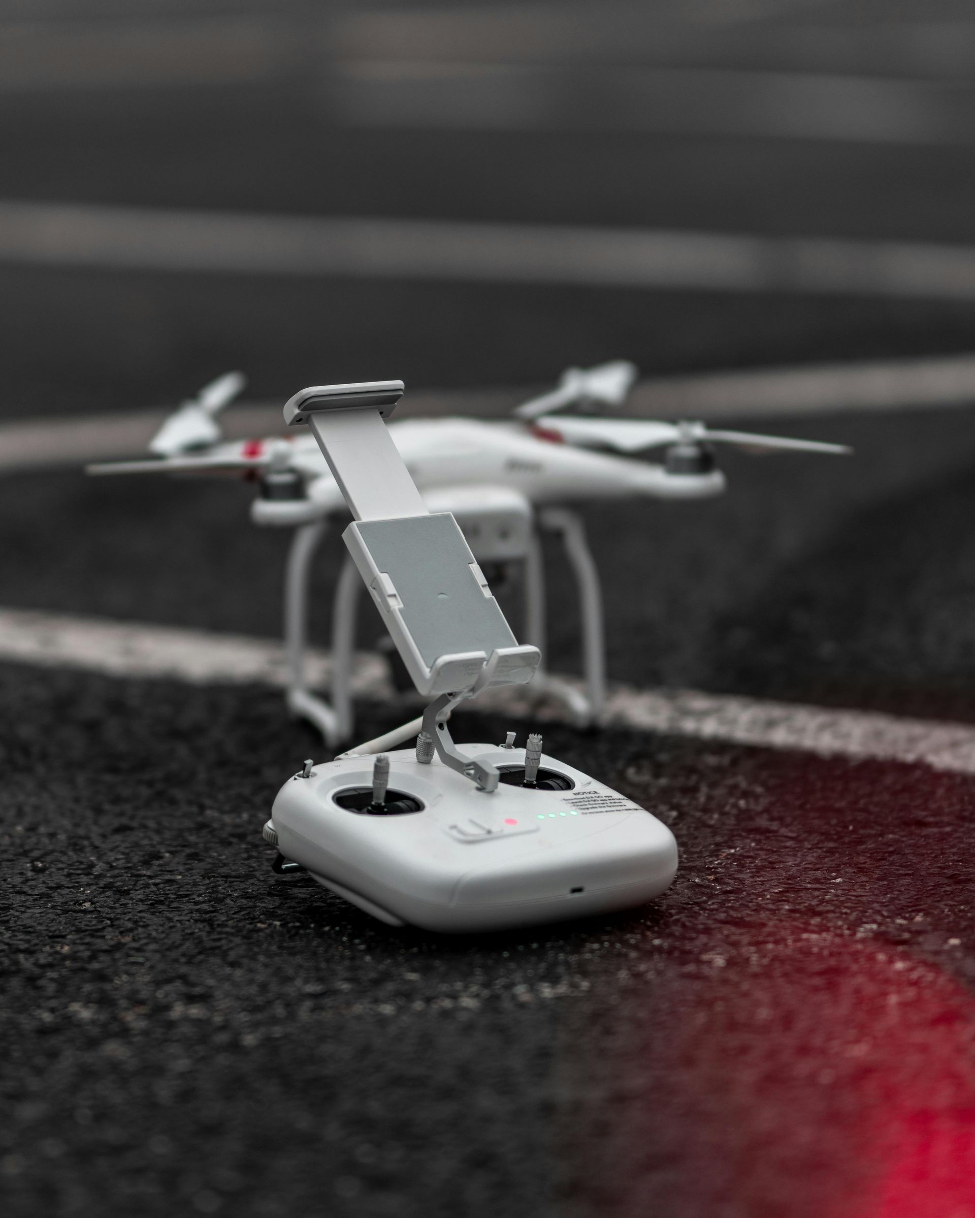 A drone is sitting on the ground next to a remote control.