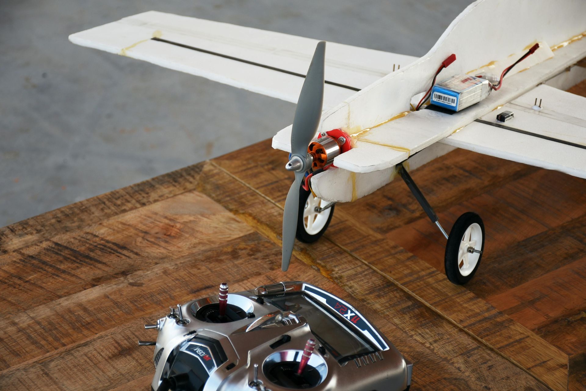 Model airplane with propeller and remote on a wood table.