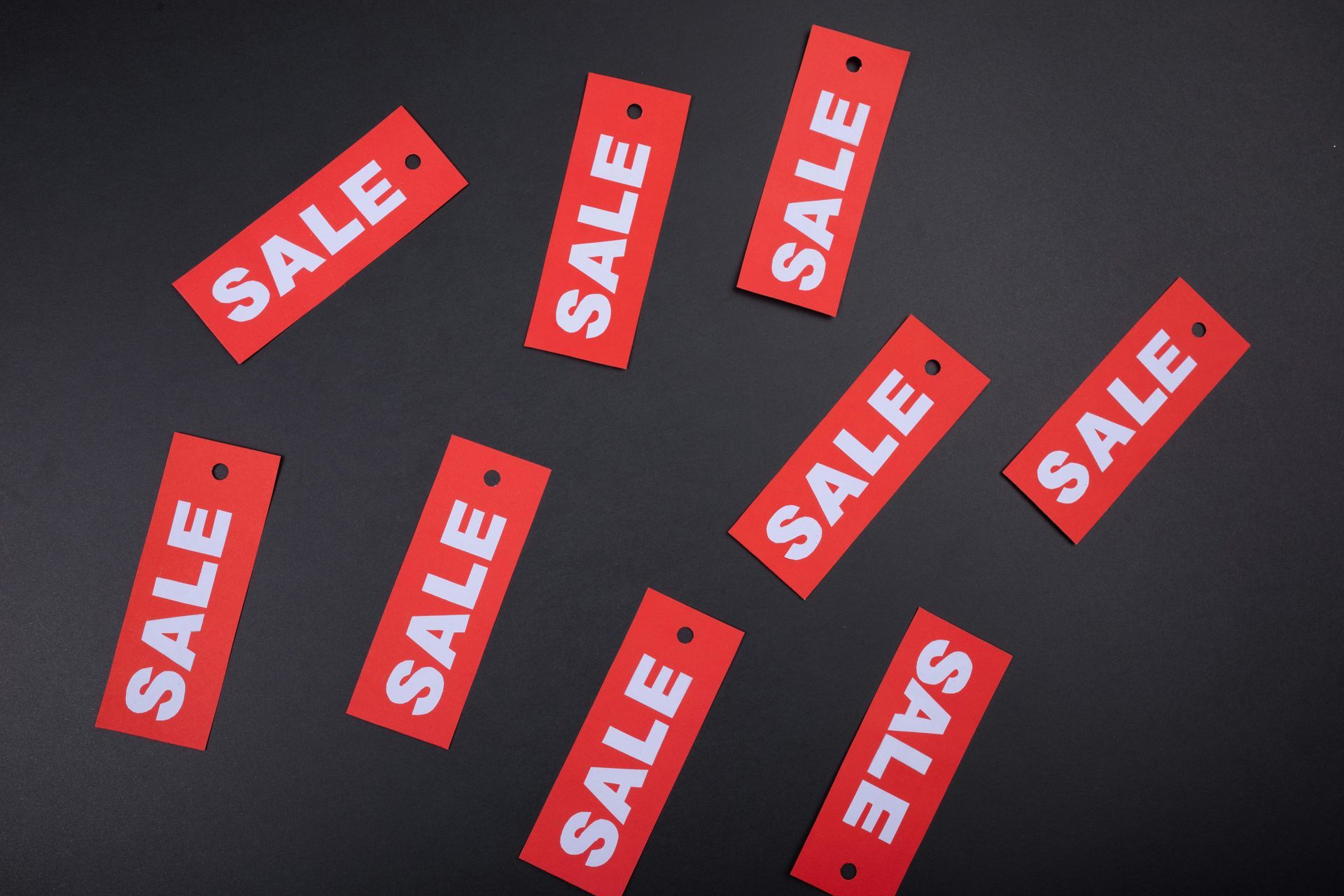 Red SALE tags scattered on a dark background