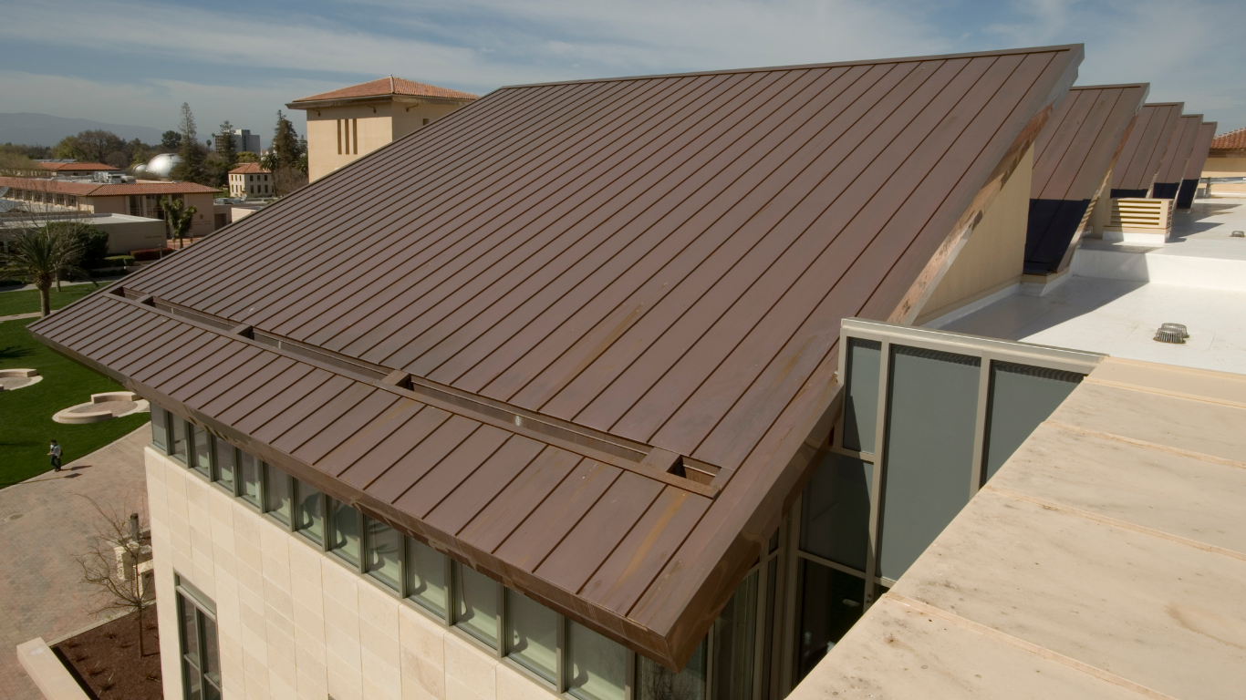Brown metal roof of a modern building with rectangular panels against a clear sky.