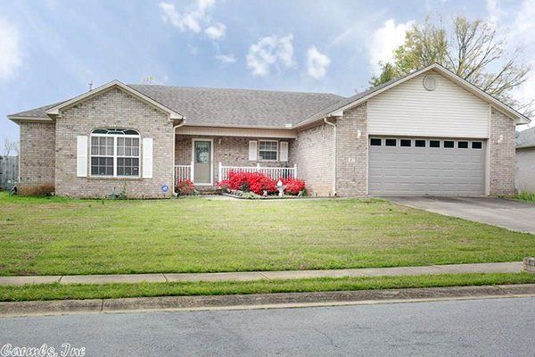 An Arkanasas home with a green lawn and flowers.