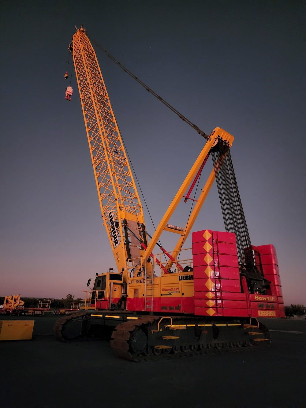 A Large Yellow And Red Crane Is Sitting In A Parking Lot — SureLift Crane Hire In Emerald, QLD