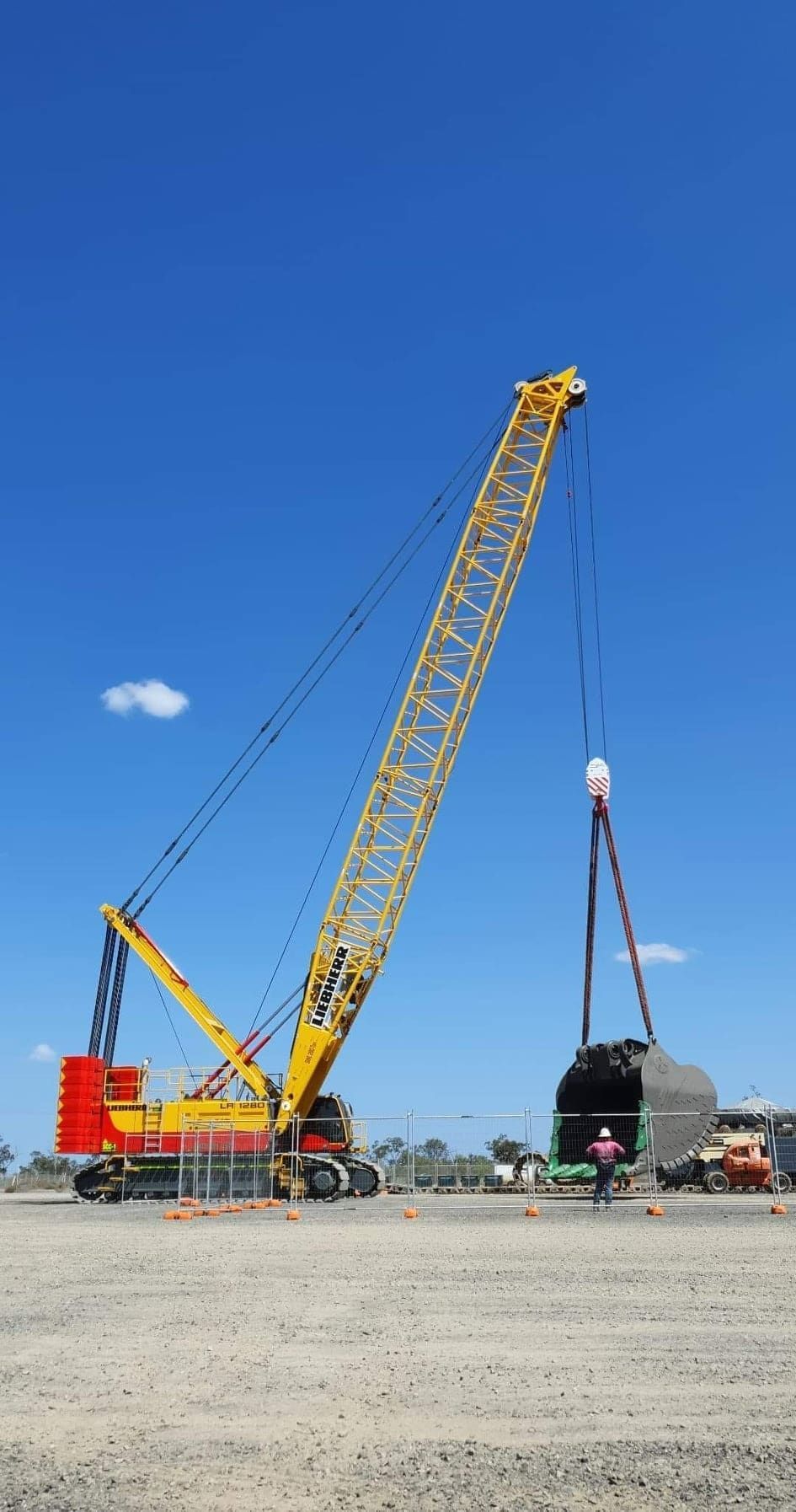 A Large Yellow Crane Is Lifting A Large Object In A Dirt Field — SureLift Crane Hire In Moranbah, QLD