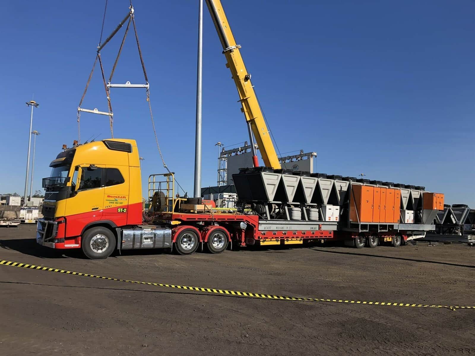A Yellow And Red Semi Truck Is Being Lifted By A Crane — SureLift Crane Hire In Mackay, QLD