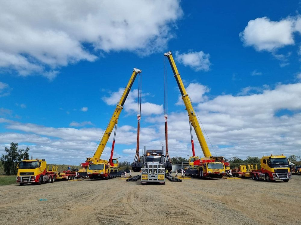 A Group Of Trucks And Cranes Are Parked In A Dirt Lot — SureLift Crane Hire In Moranbah, QLD