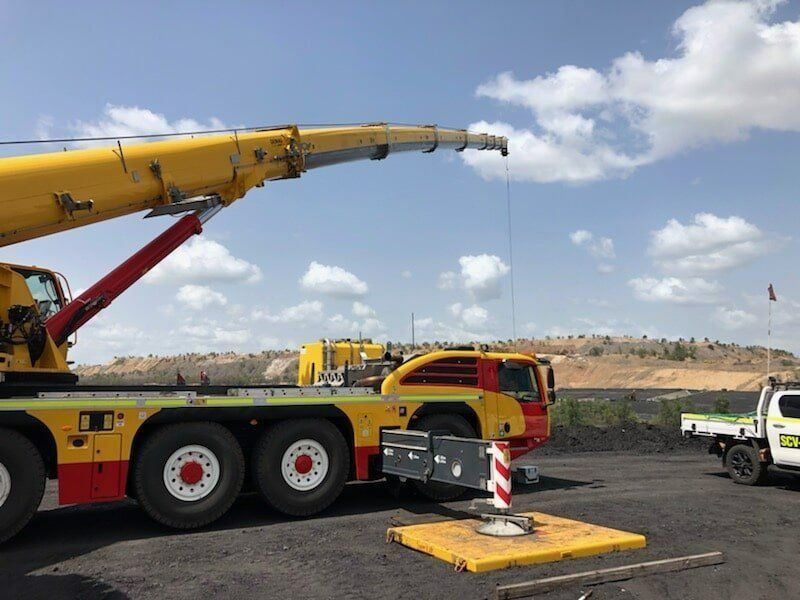 A Yellow And Red Crane Is Parked In A Parking Lot — Surelift Crane Hire In Moranbah, QLD