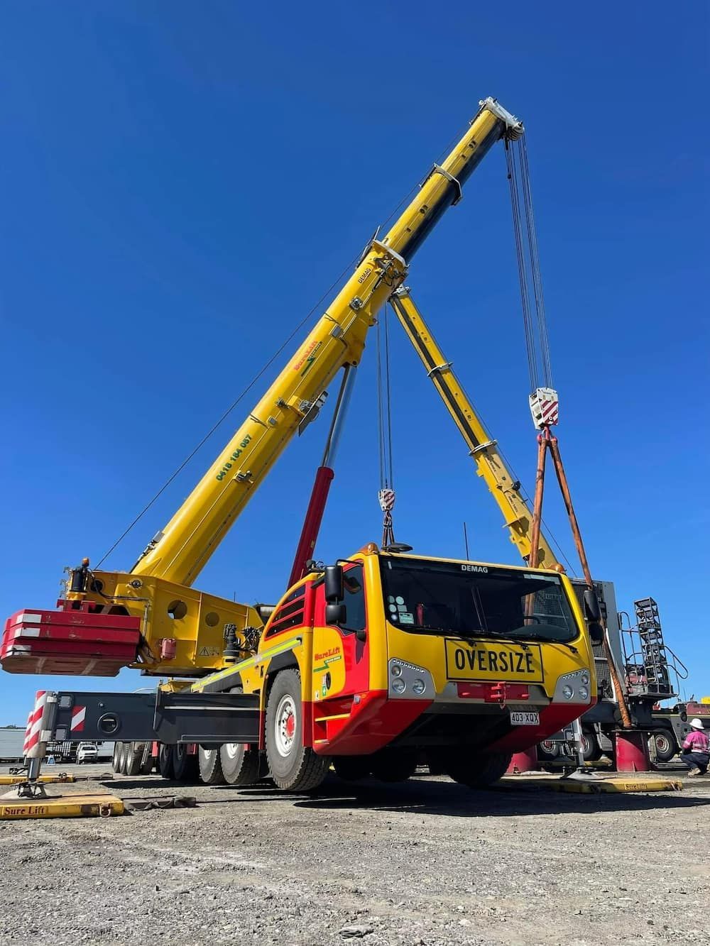 A Yellow And Red Truck With A Crane Attached To It — SureLift Crane Hire In Mackay, QLD