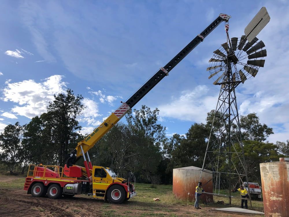 A Crane Is Lifting A Windmill In A Field — SureLift Crane Hire In Moranbah, QLD