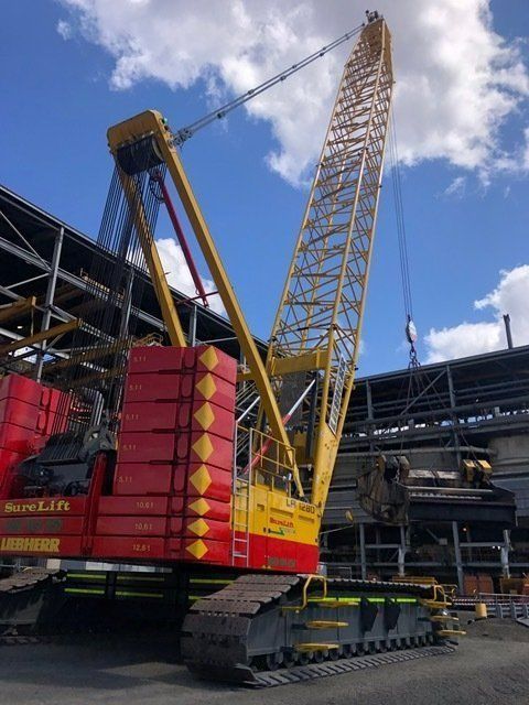 A Red And Yellow Crane Is Parked In Front Of A Building — Surelift Crane Hire In Moranbah, QLD
