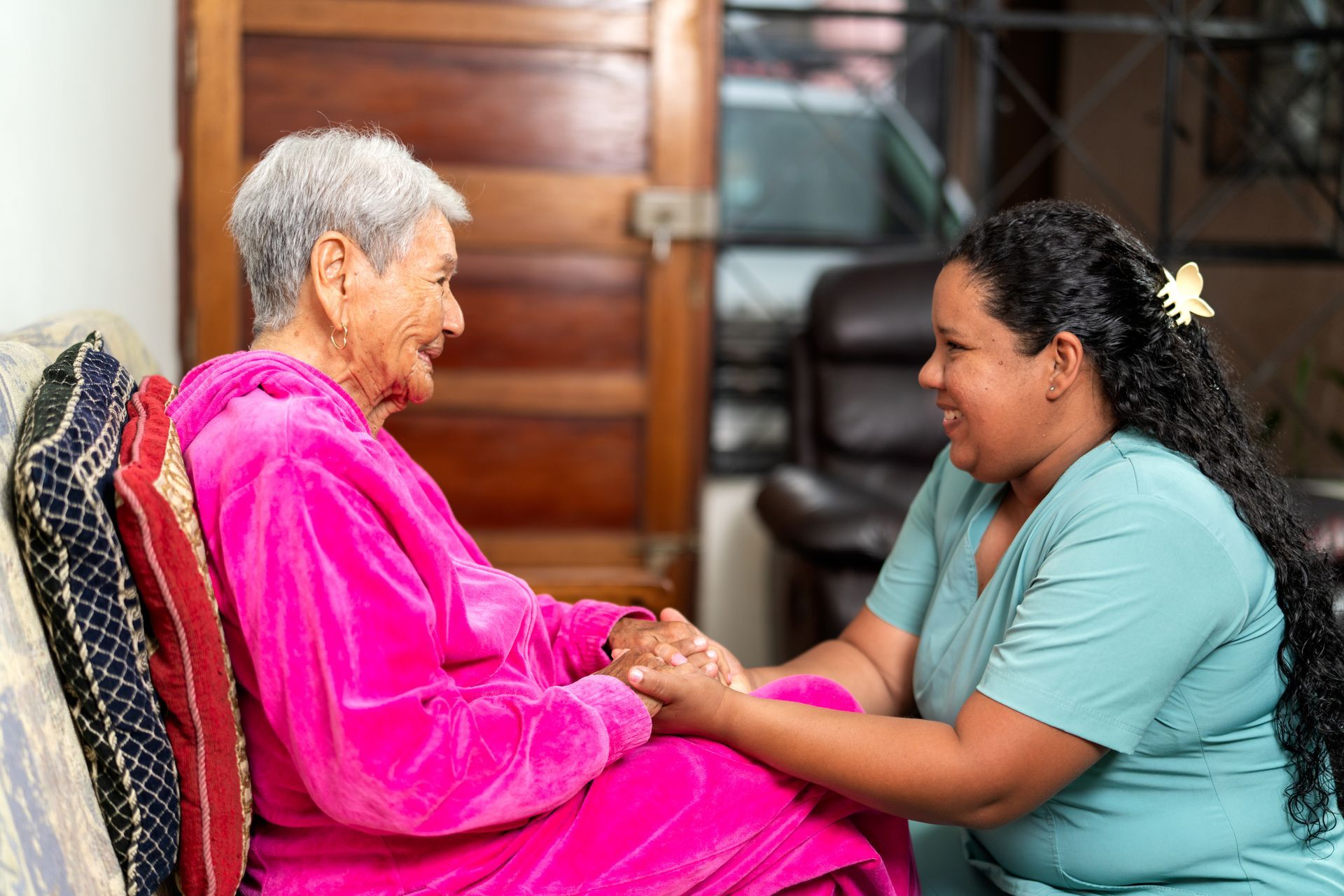 Smiling older adult in a wheelchair writing at a table with a person next to her, indoor setting Smiling older adult in a wheelchair writing at a table with a person next to her, indoor setting