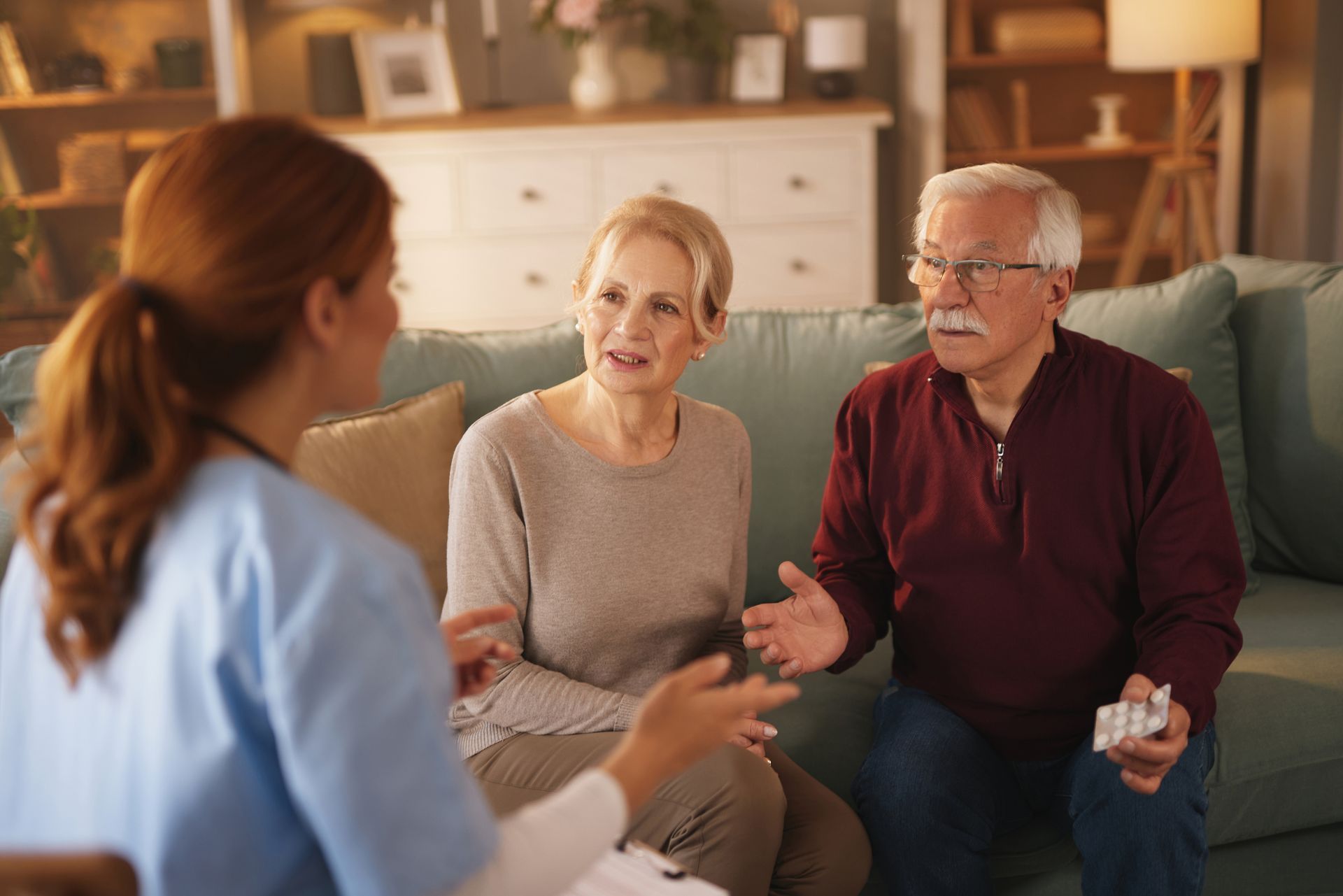 Nurse consulting with senior couple on a sofa, discussing medication.