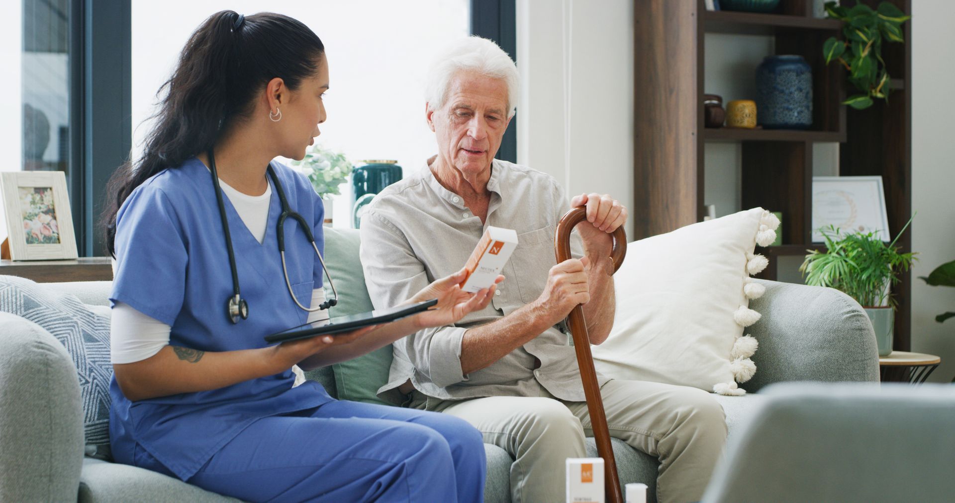 A healthcare worker reviews medication with an older person, indoors. A healthcare worker reviews medication with an older person, indoors.