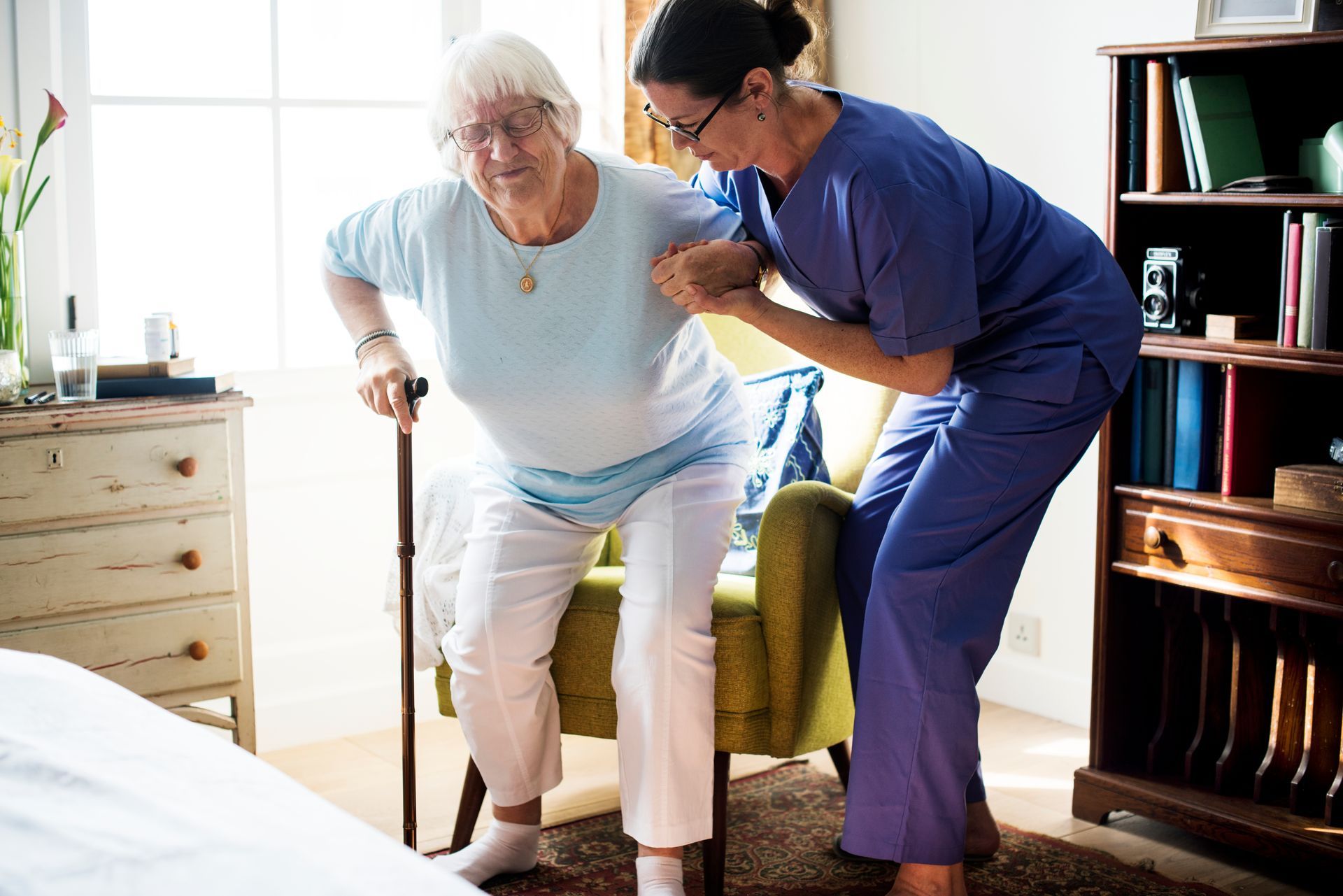Woman in wheelchair smiles at caregiver in a sunny outdoor setting