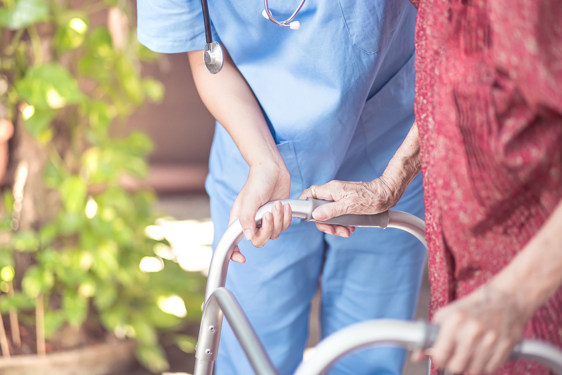 Nurse assisting an elderly person using a walker outdoors Nurse assisting an elderly person using a walker outdoors