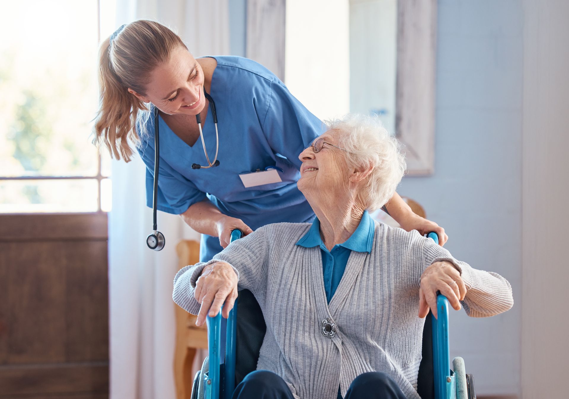 Nurse assists an elderly person in a wheelchair indoors Nurse assists an elderly person in a wheelchair indoors