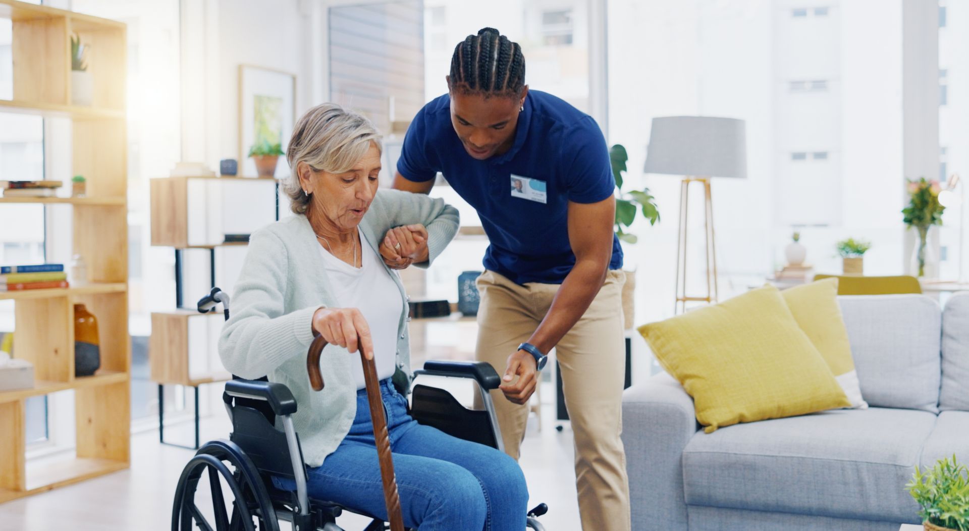 Caregiver assists a person using a wheelchair to stand