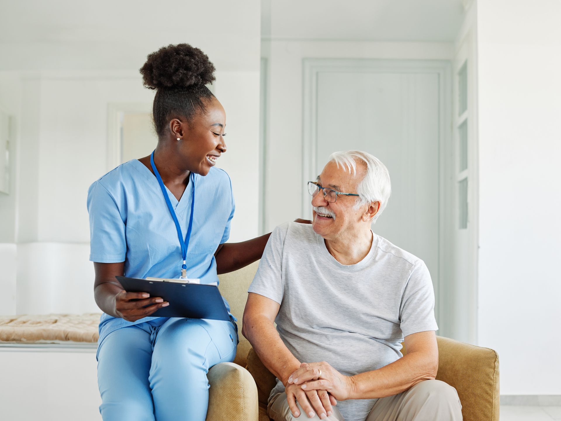 Woman points at document, smiling at older woman wearing glasses. Indoors, neutral tones.
