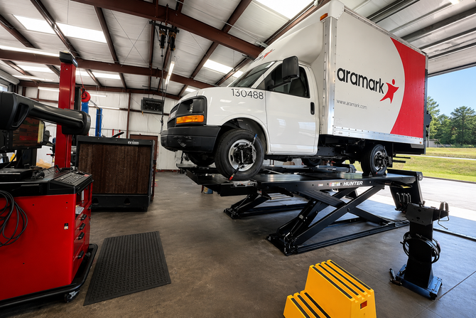 White service van lifted on a shop hoist inside a vehicle repair garage in LaGrange Ga