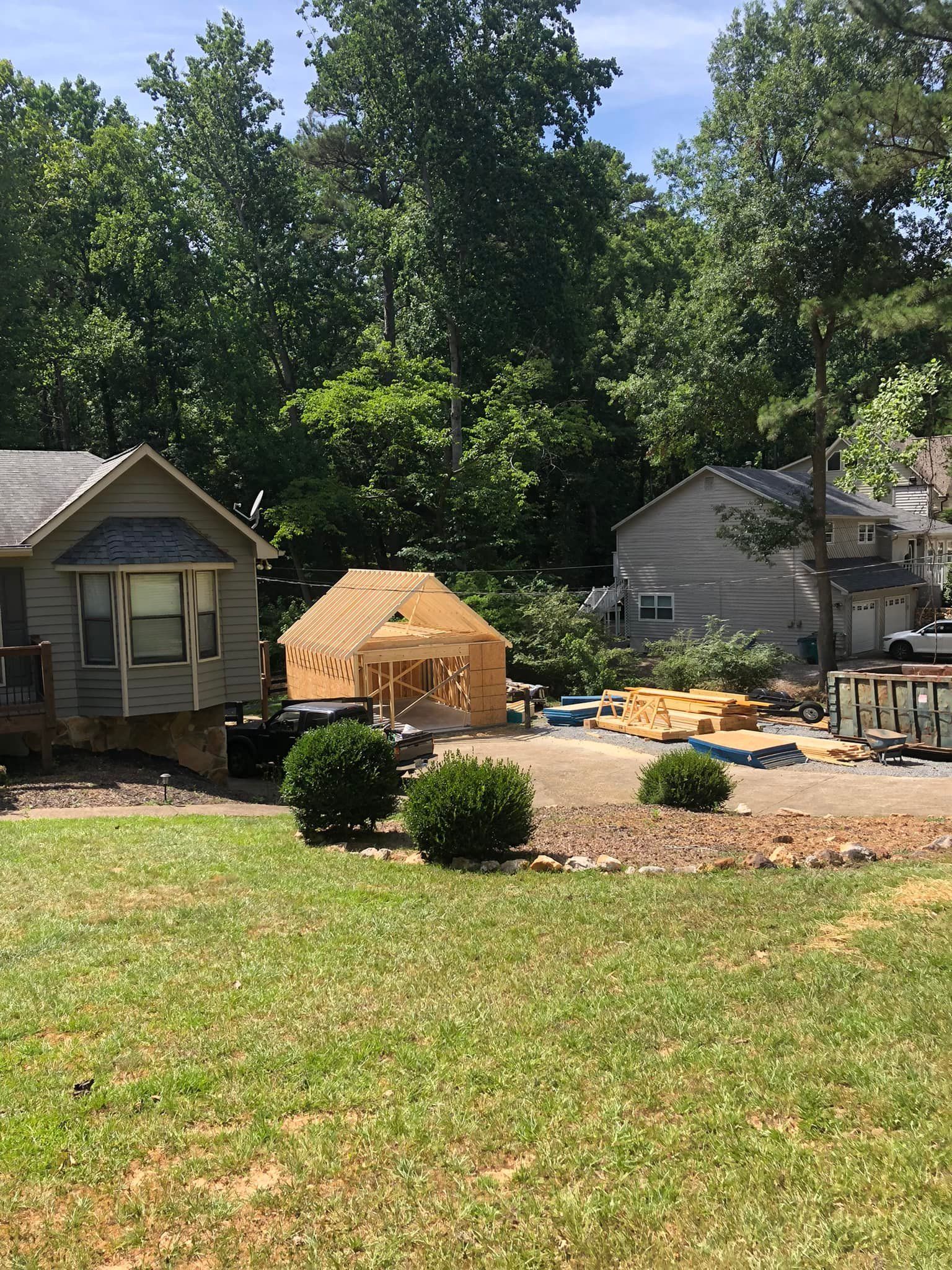 Backyard scene with a wooden shed under construction; trees and houses in the background.
