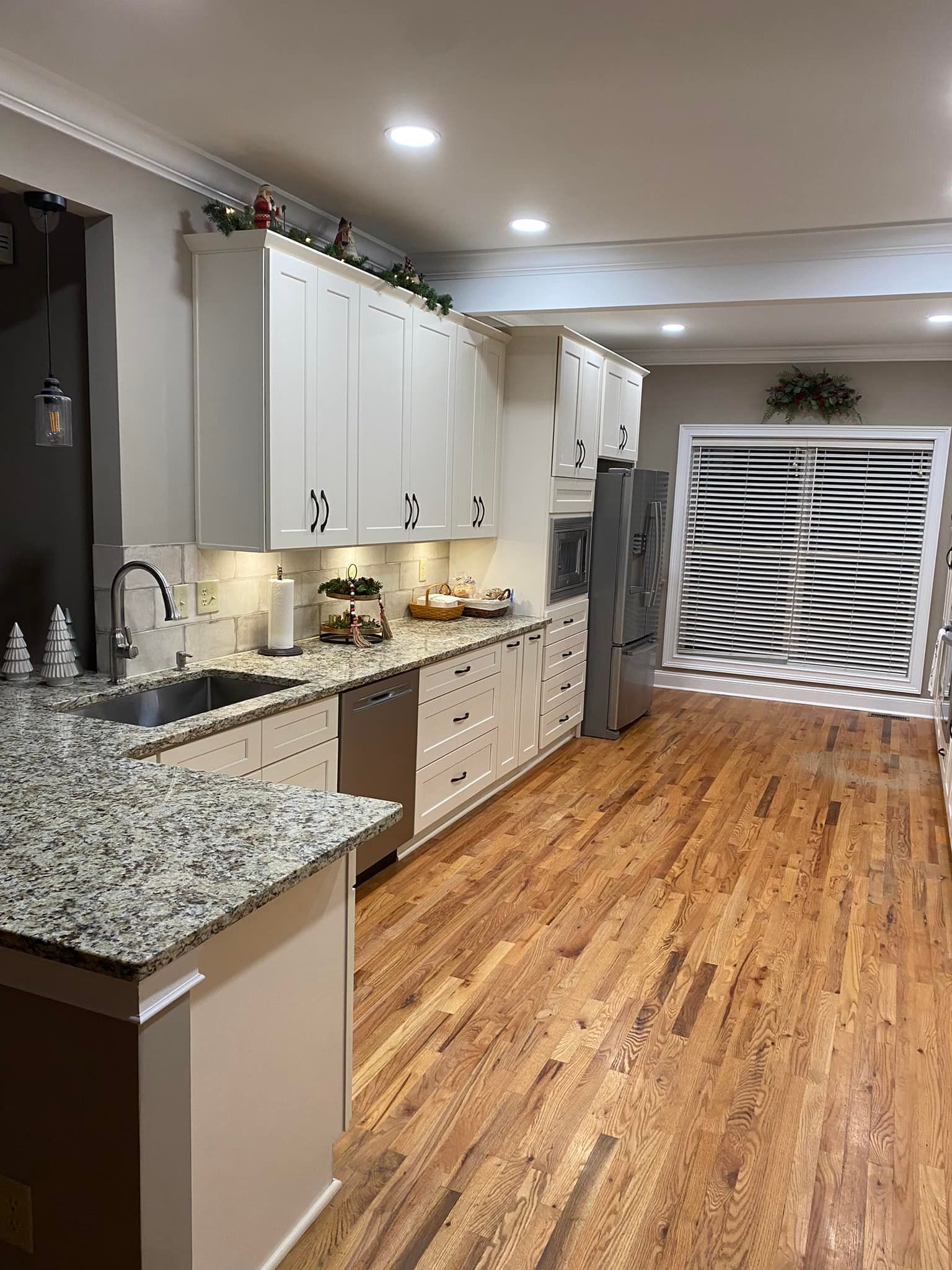 Kitchen with white cabinets, granite countertops, stainless steel appliances, and wood floors,