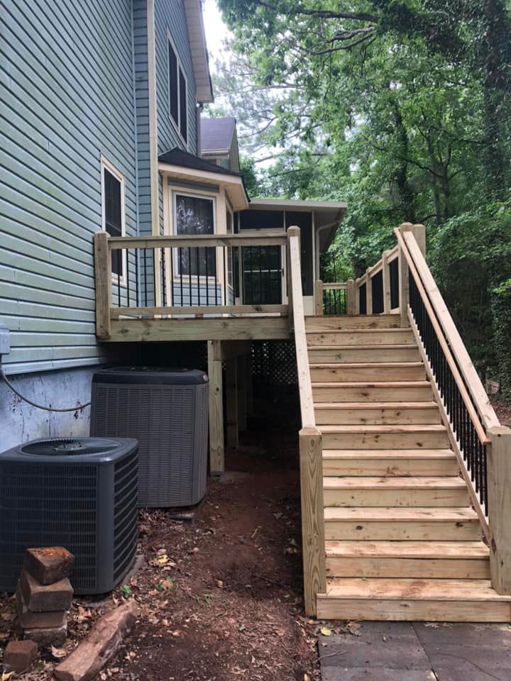 Newly constructed wooden deck and stairs leading to a light blue house. Two air conditioning units sit below the deck.