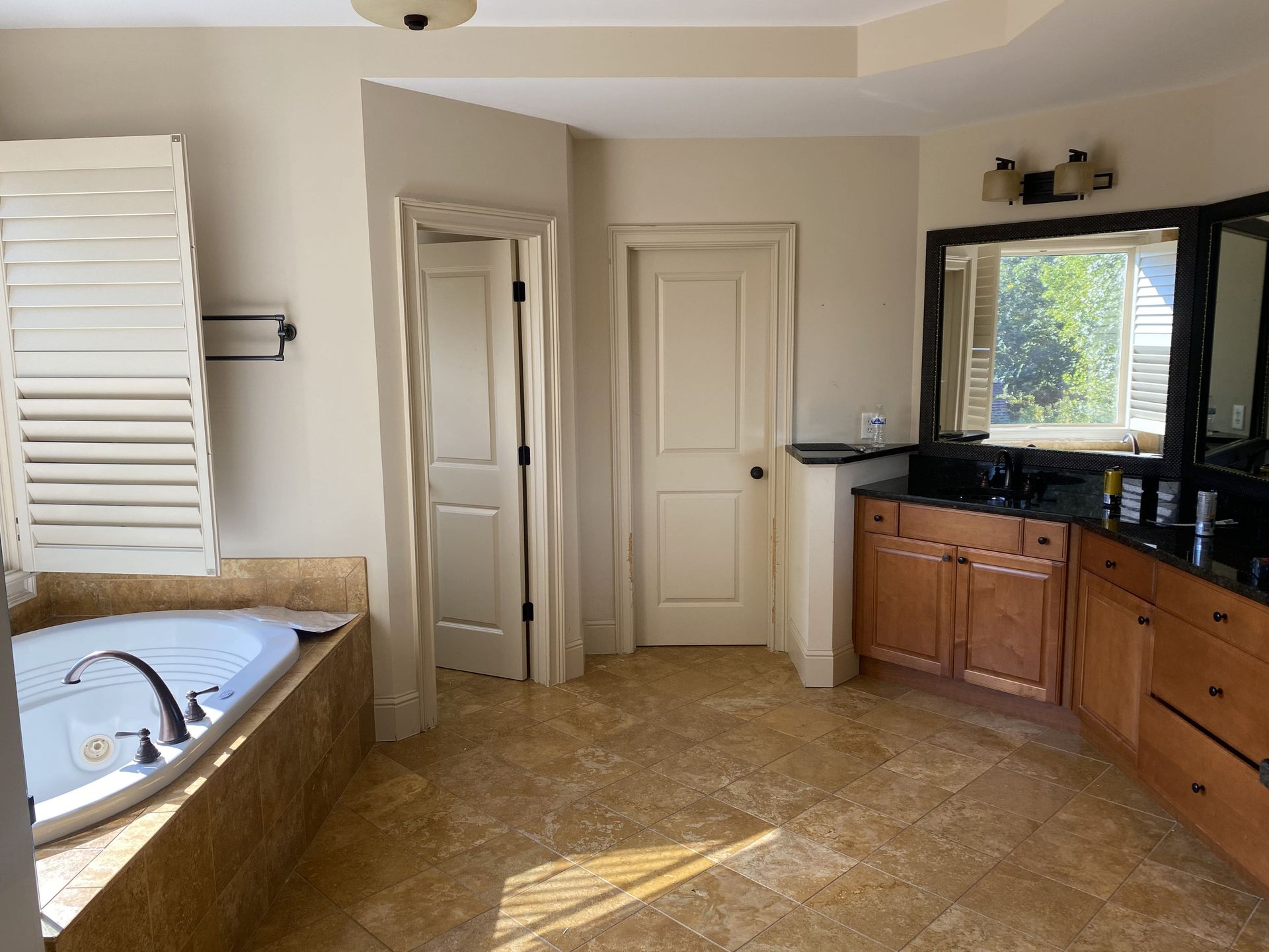 Bathroom with tub, vanity, and two doors. Light brown floor, cream walls, and wood cabinets.