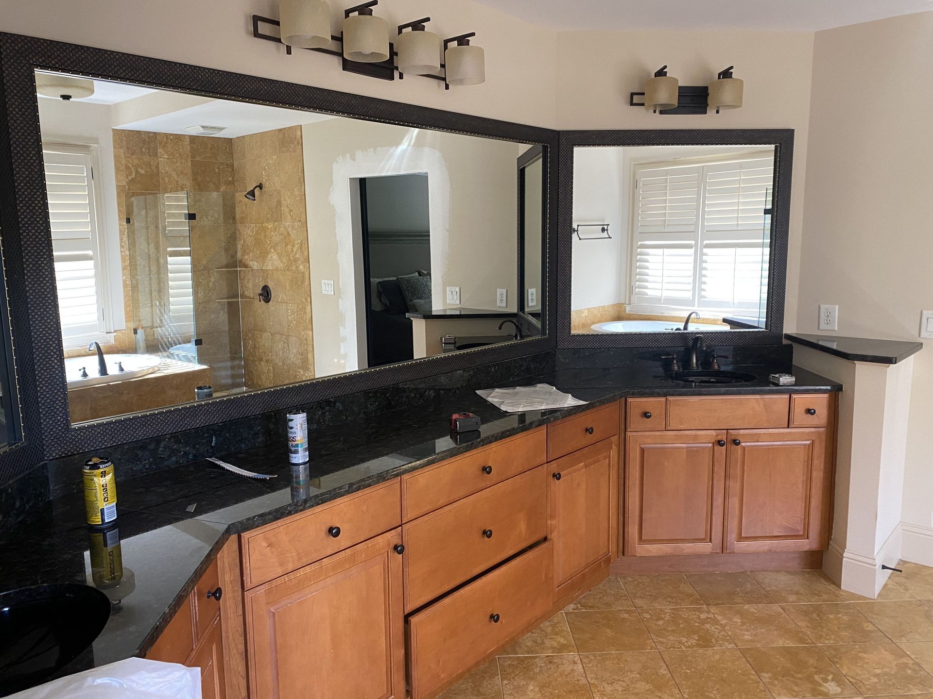 Bathroom with brown cabinets, dark countertop, and large mirrors.