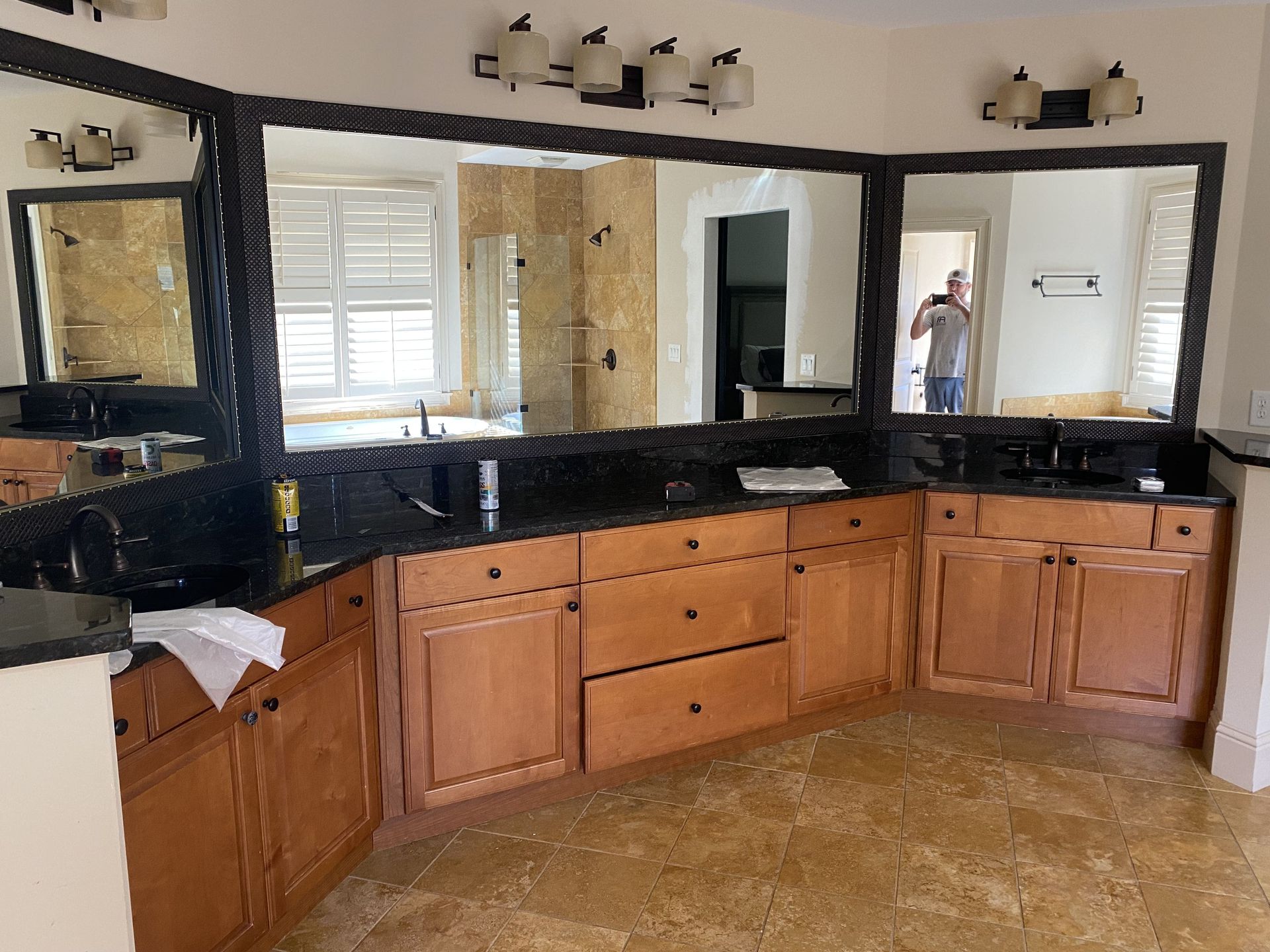 Bathroom with a black countertop, mirrors, and wooden cabinets.