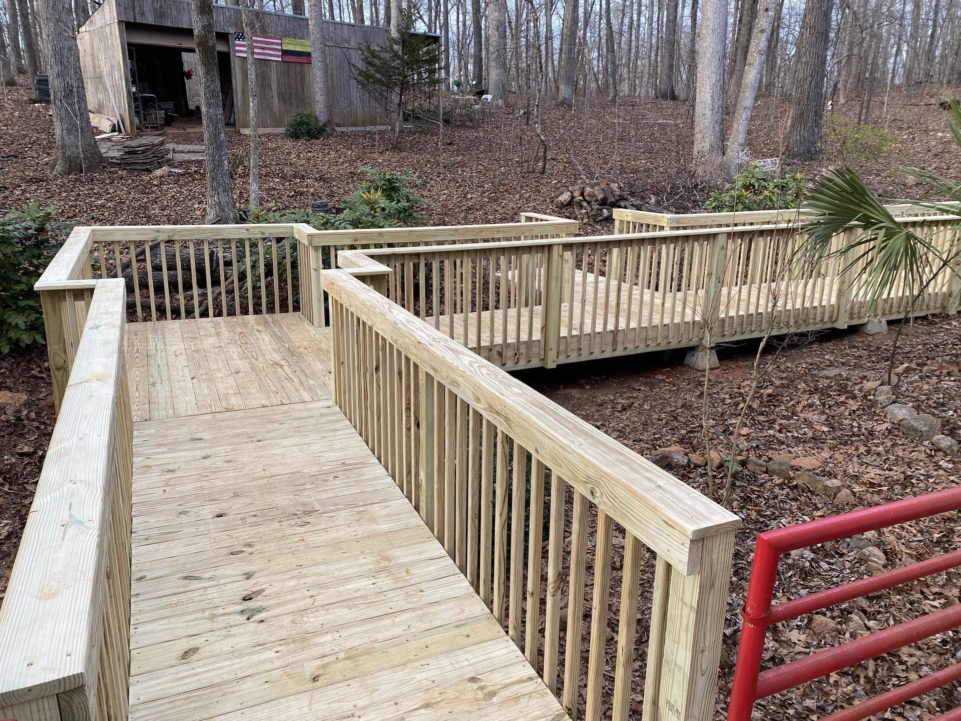 Wooden ramp with railings in a wooded area.  Newly constructed and leading to a building.