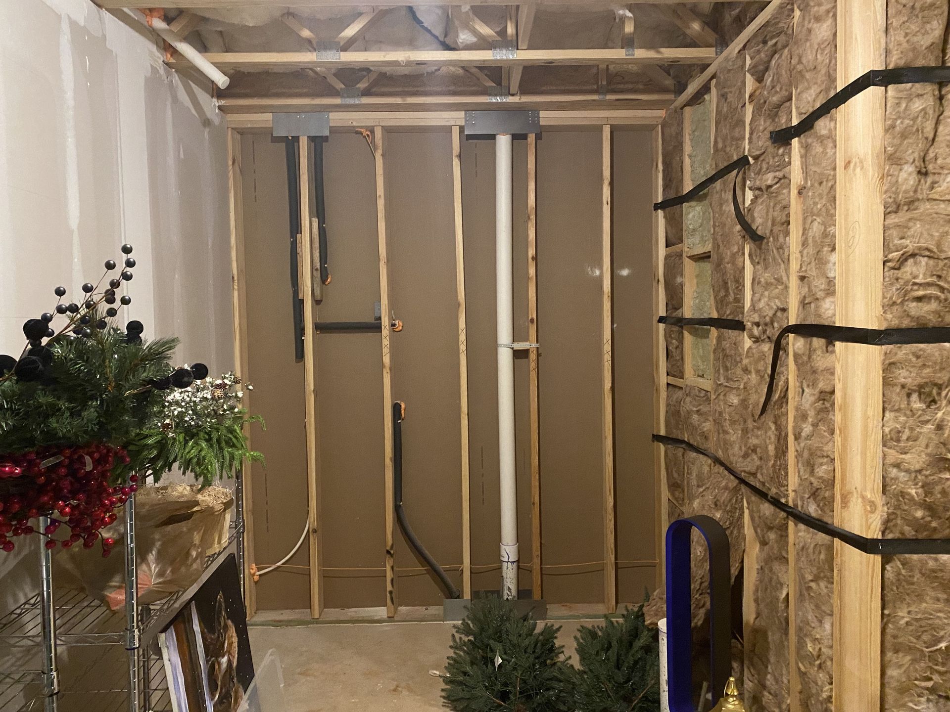 Basement with exposed framing, pipes, and wiring. Drywall partially installed.