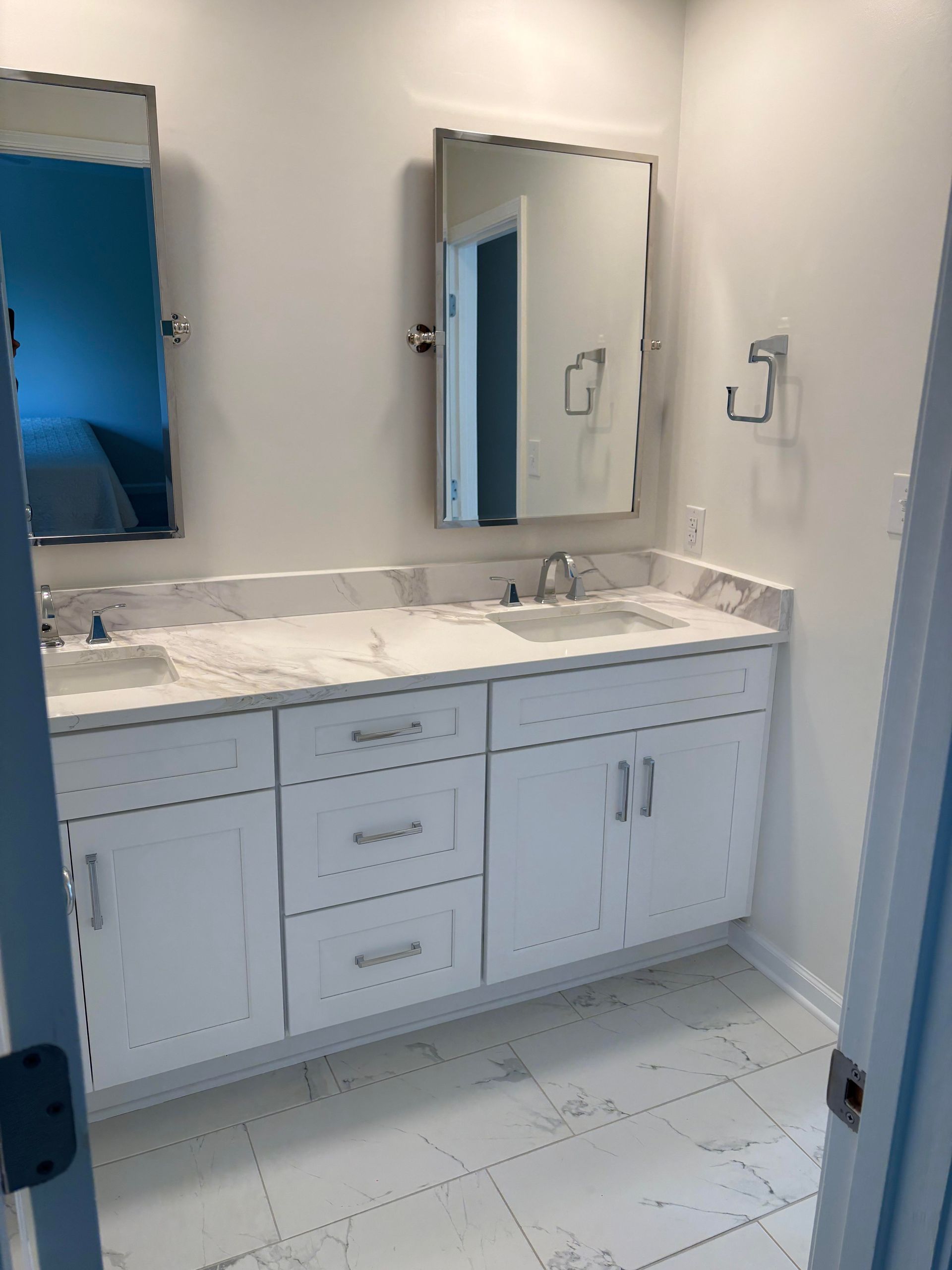 White bathroom with double sink vanity, marble countertop, and rectangular mirrors.