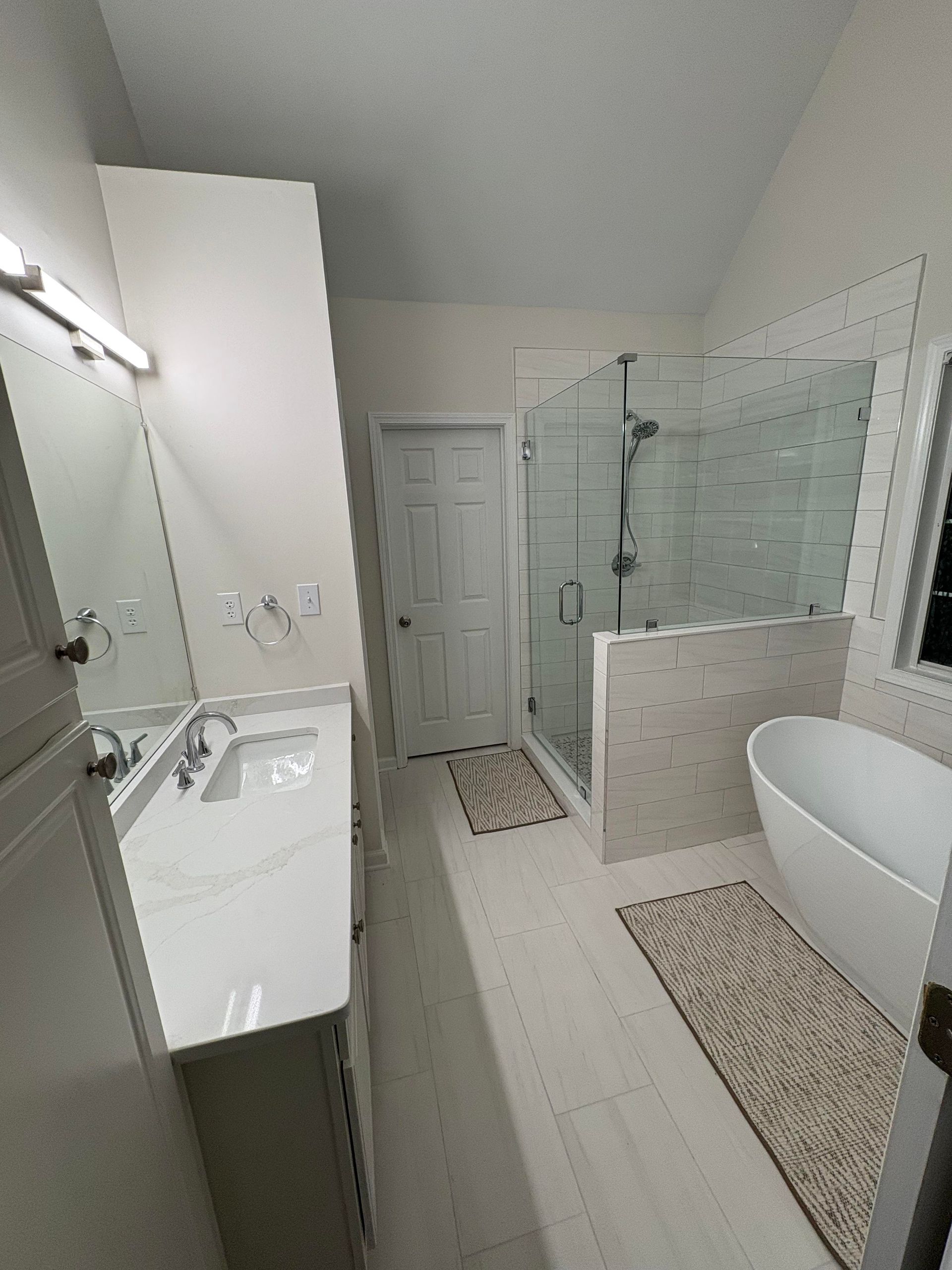 Modern bathroom with white walls, vanity, shower, and freestanding tub.
