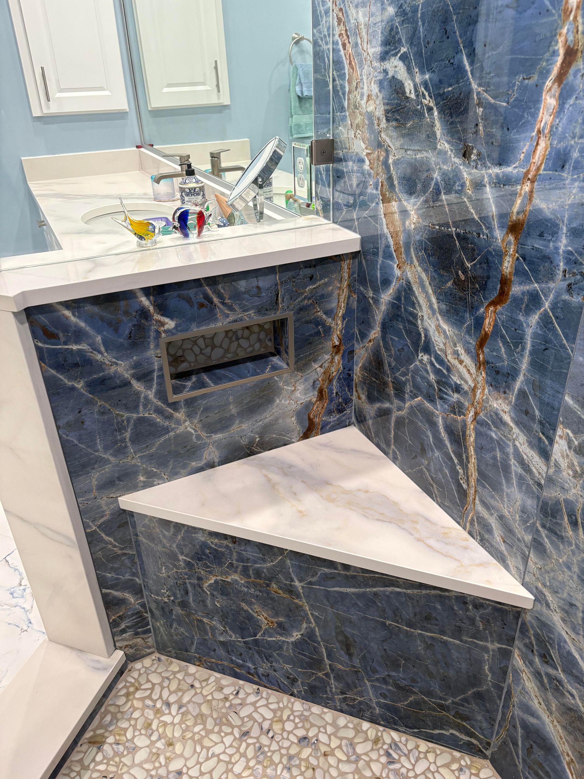 Blue marble shower with a white countertop and triangular built-in seat.