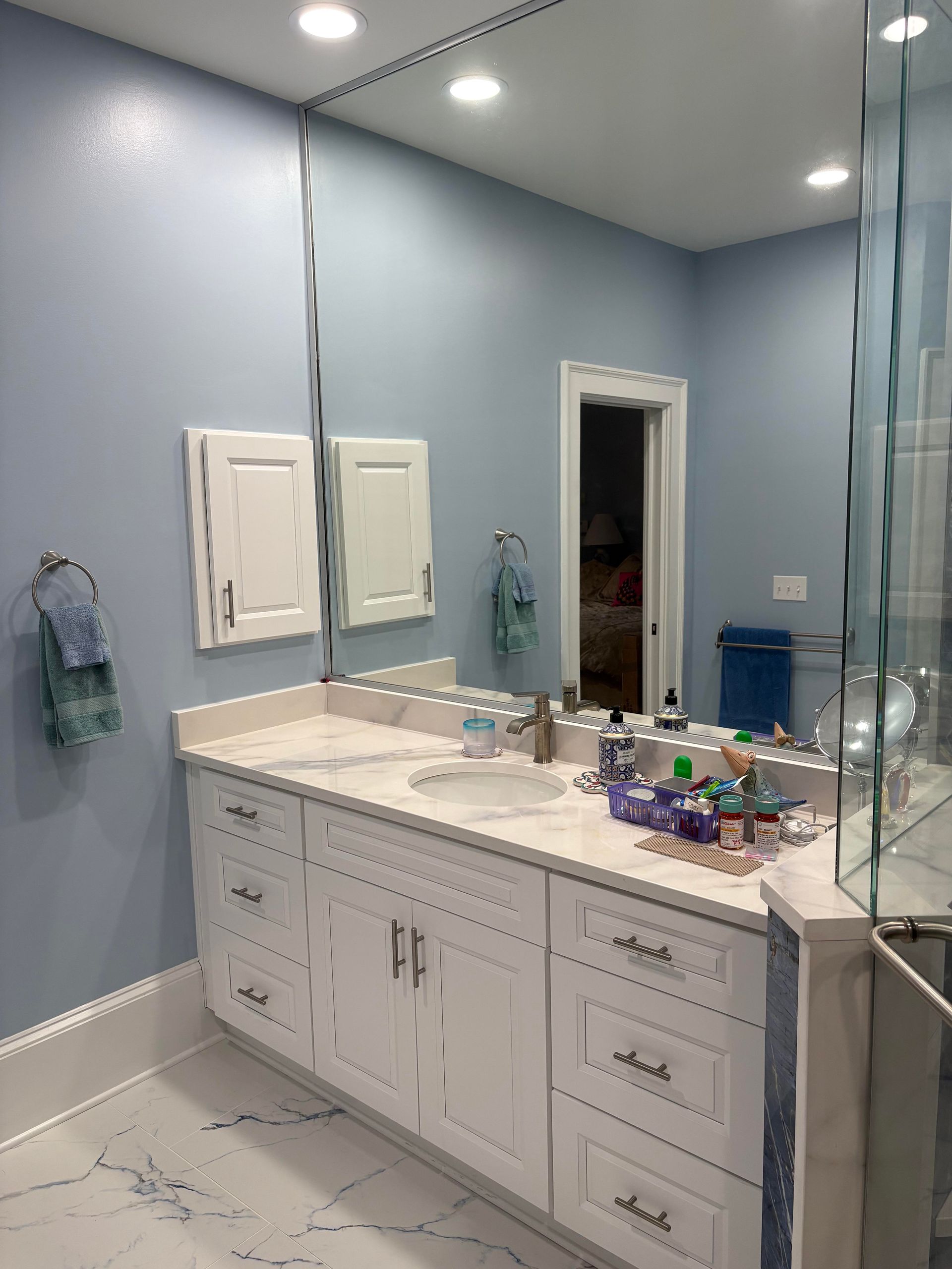 Bathroom with white vanity, large mirror, and blue walls.