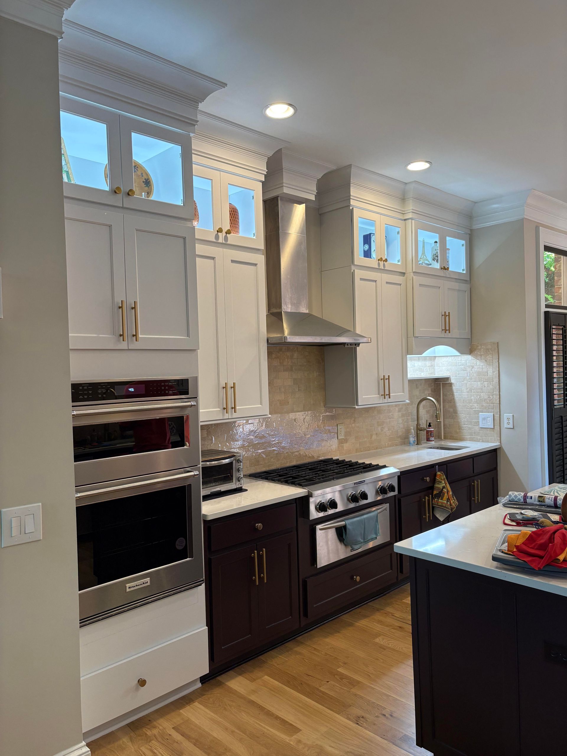 Modern kitchen with white and dark brown cabinets, stainless steel appliances, and a range hood.