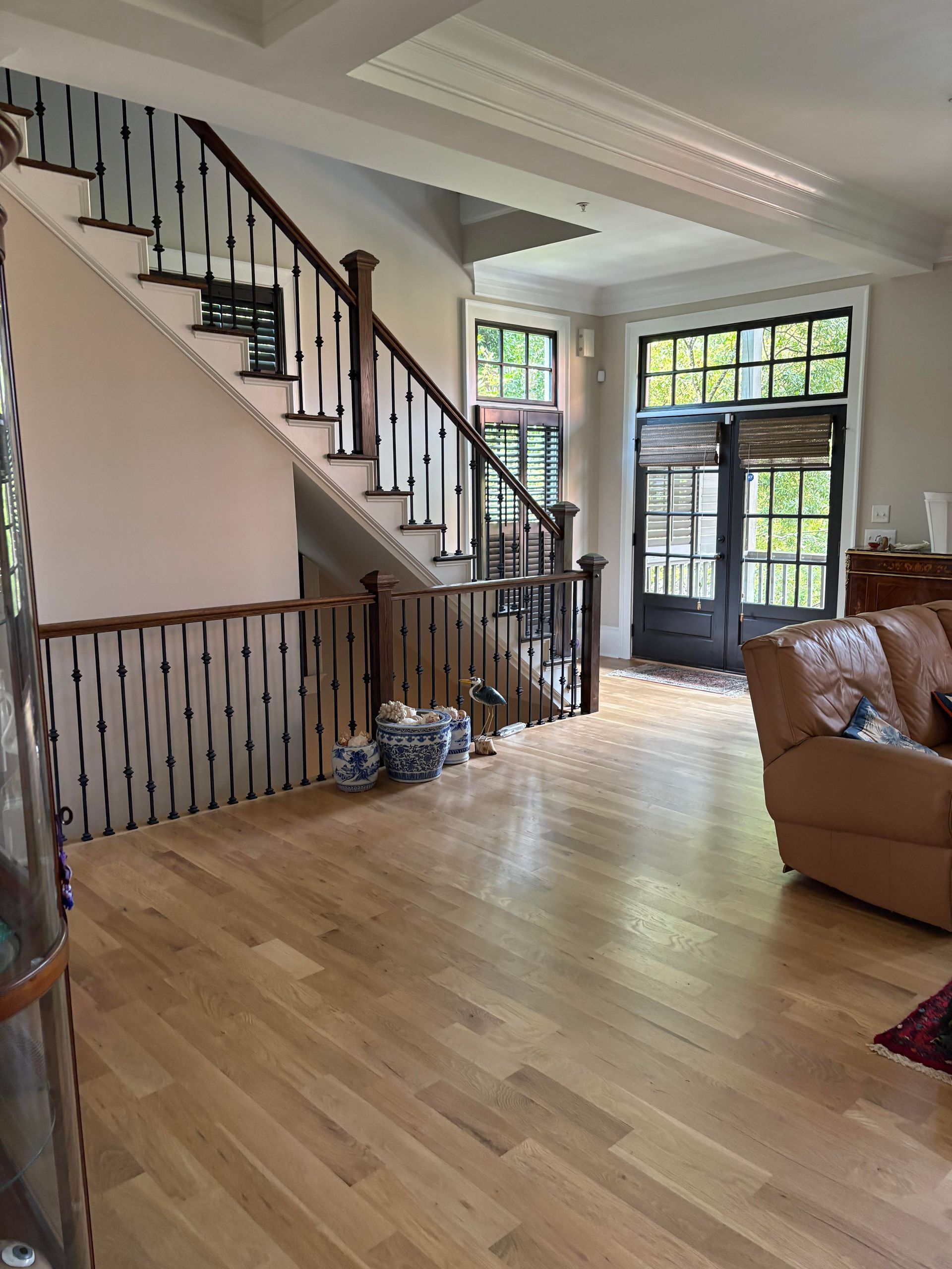 Interior with wooden floors, staircase with dark handrails, and glass-paned doors.