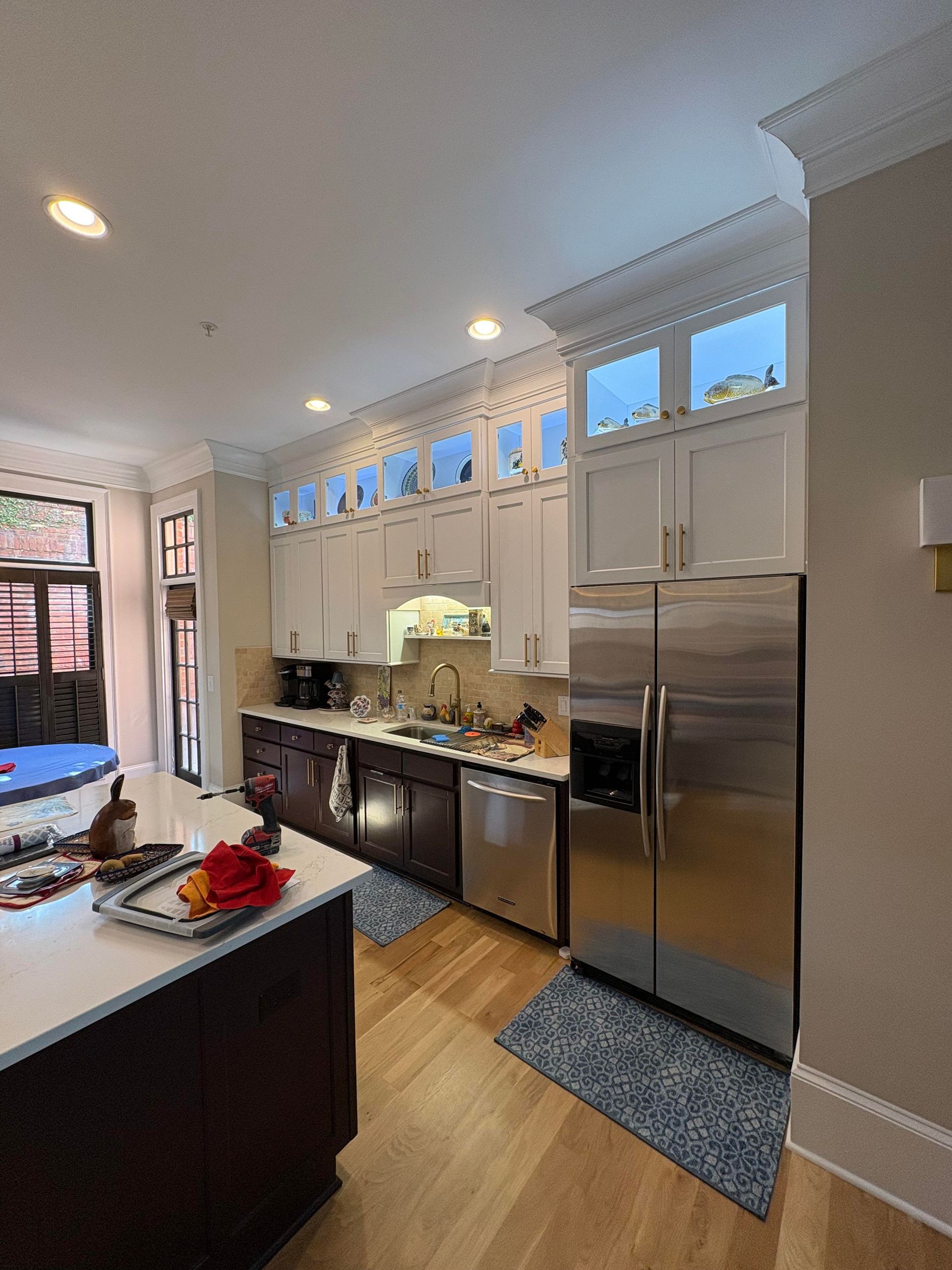 Kitchen with white cabinets, stainless steel appliances, and island with white countertop.