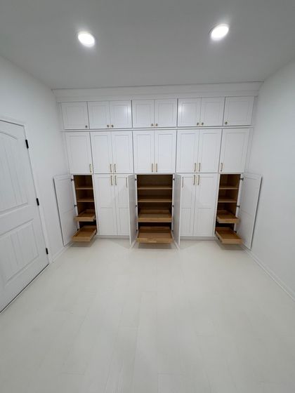 White storage cabinets line a white-walled room; some doors are open revealing shelves.
