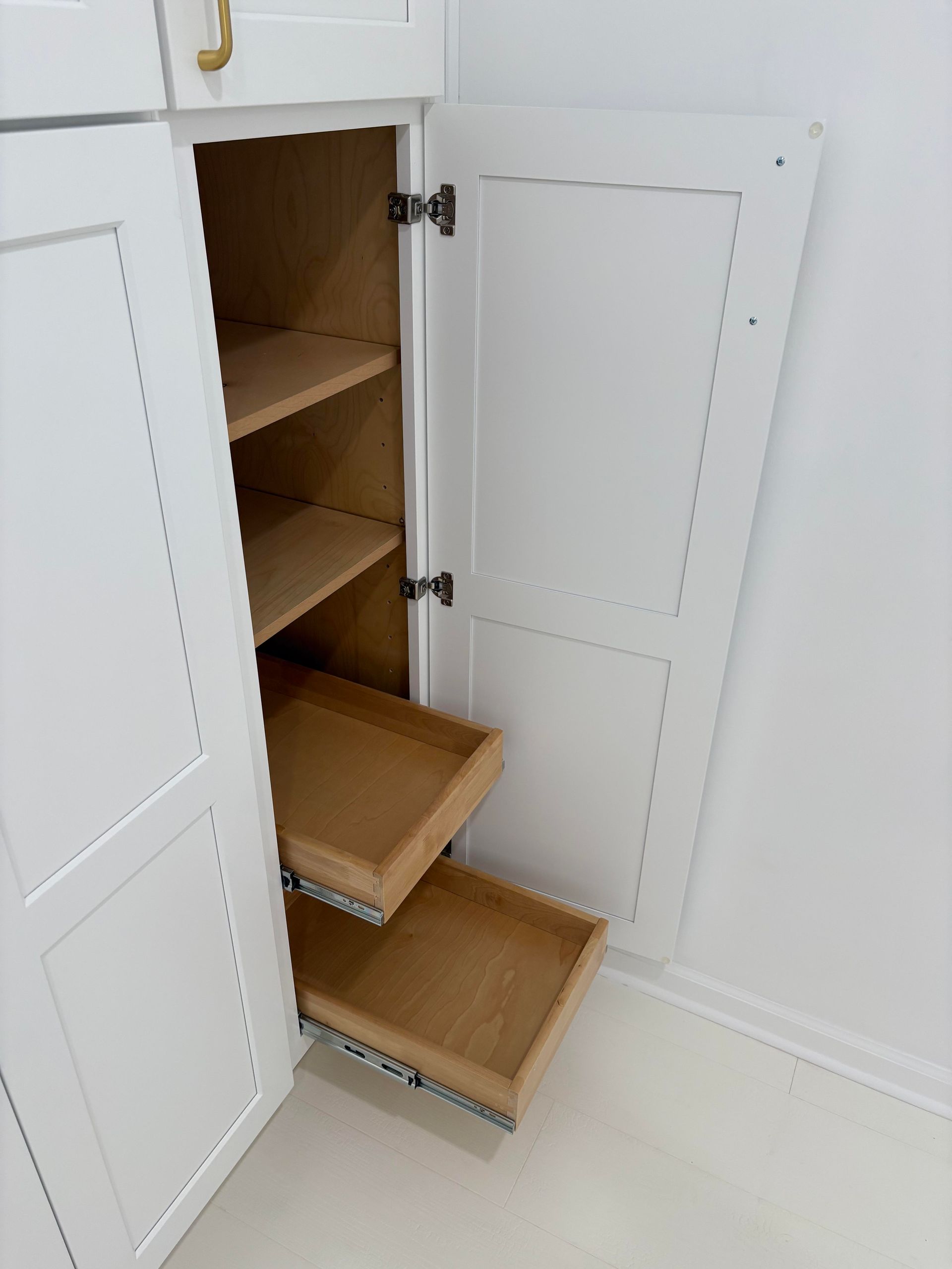 White pantry cabinet with open door revealing shelves and pull-out drawers.