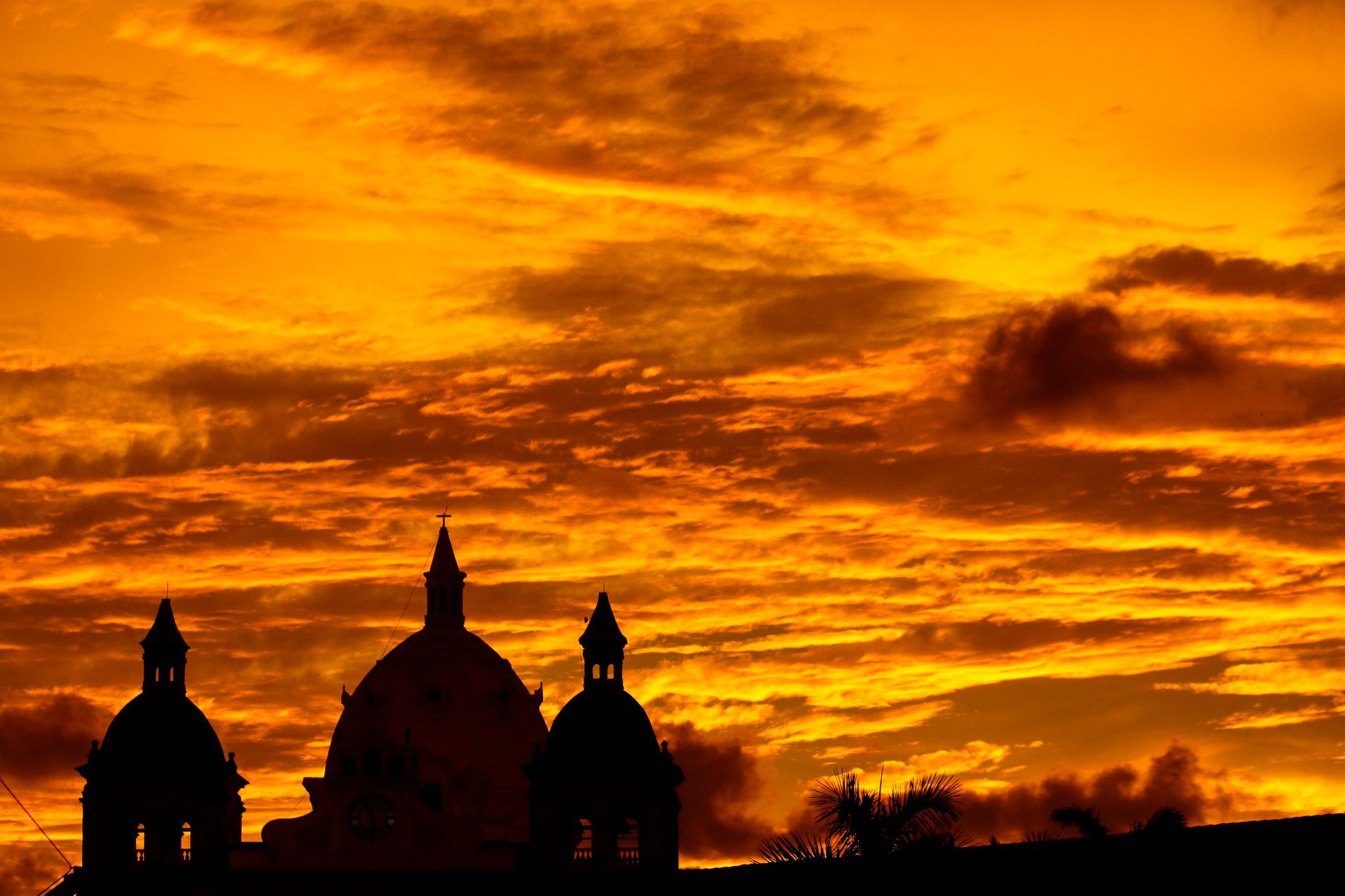 Siluetas de cúpulas recortadas contra un atardecer de color naranja intenso.
