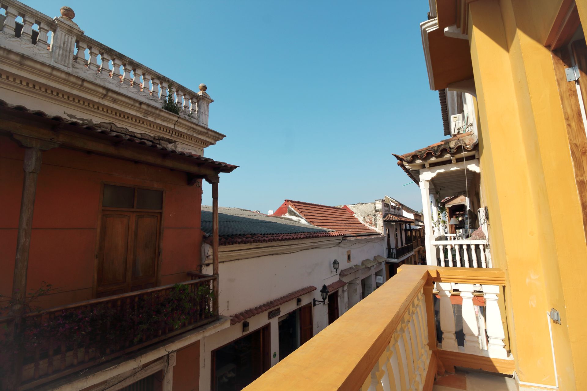 Vista desde un balcón con vistas a una calle estrecha de Cartagena, Colombia; edificios con balcones, fachadas coloridas.