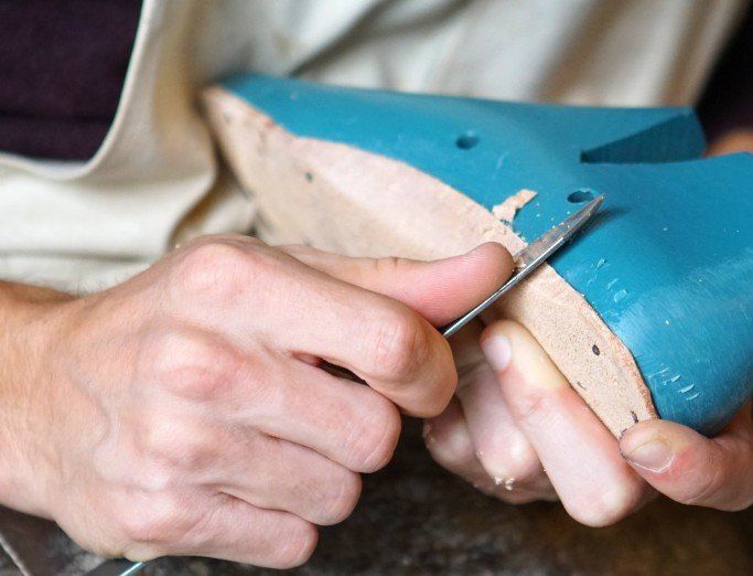 A woodworker shapes a wooden orthotic form with a knife. A form is made by a woodworker for a orthotics insert.
