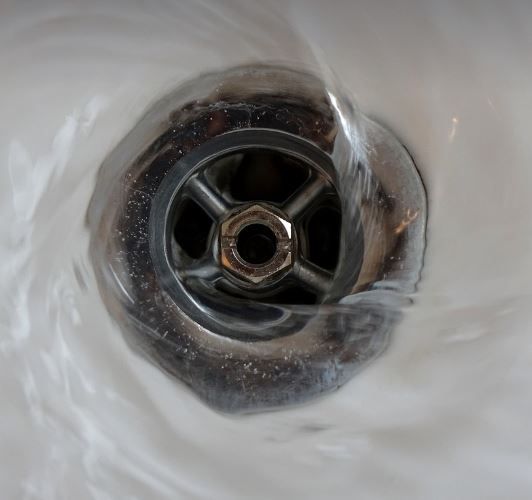 Water swirling down a shiny, metallic sink drain.