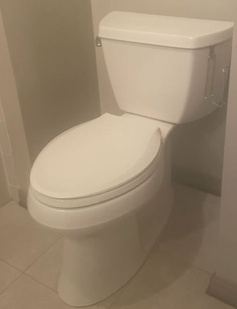 White toilet in a bathroom with a closed lid.