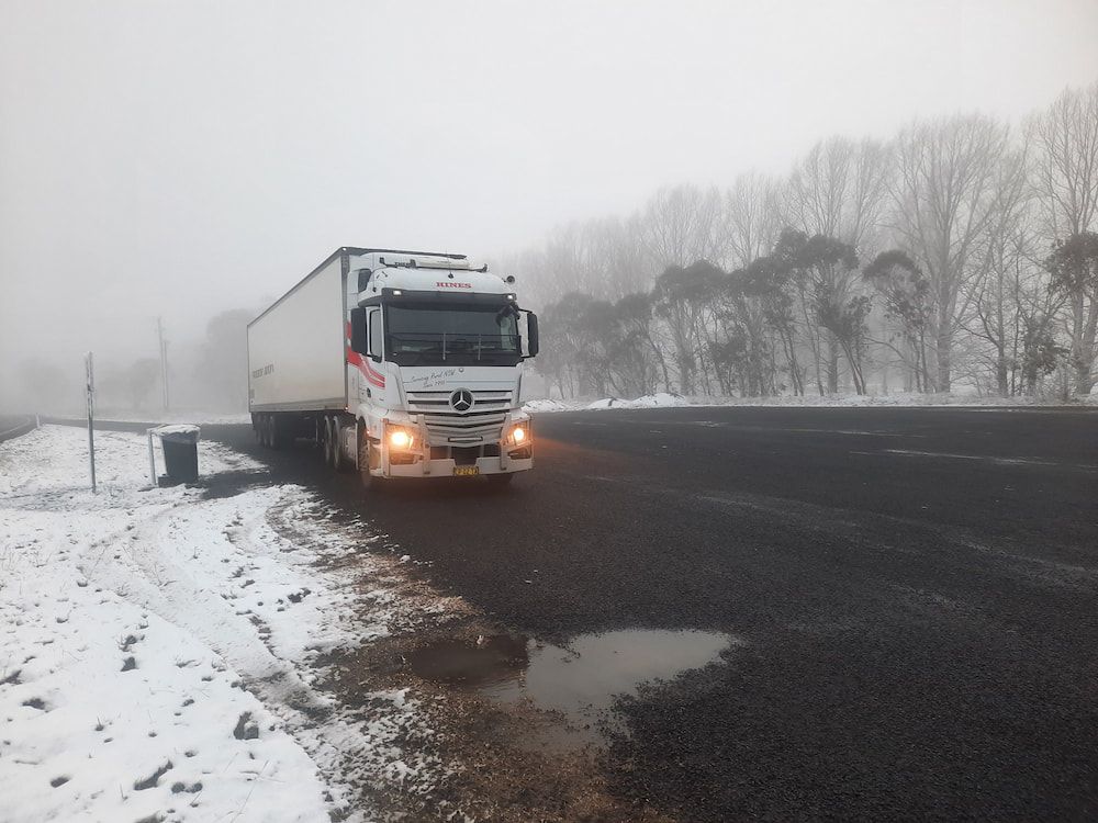 Semi-truck on Snowy Road, Fog in Background, Trees on Right — Hines Refrigerated Transport Pty Ltd in Sydney, NSW