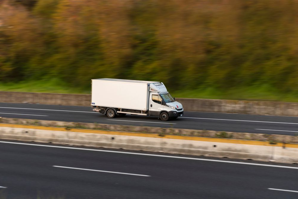 White Box Truck Driving on a Highway, Trees in the Background — Hines Refrigerated Transport Pty Ltd in Taree, NSW